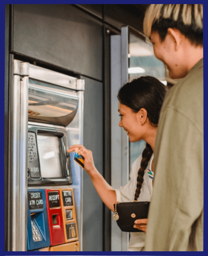 A woman using ATM machine and a man looking at it