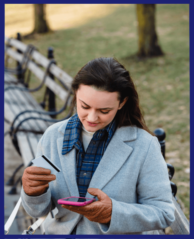A woman sitting in a park with her mobile and a card