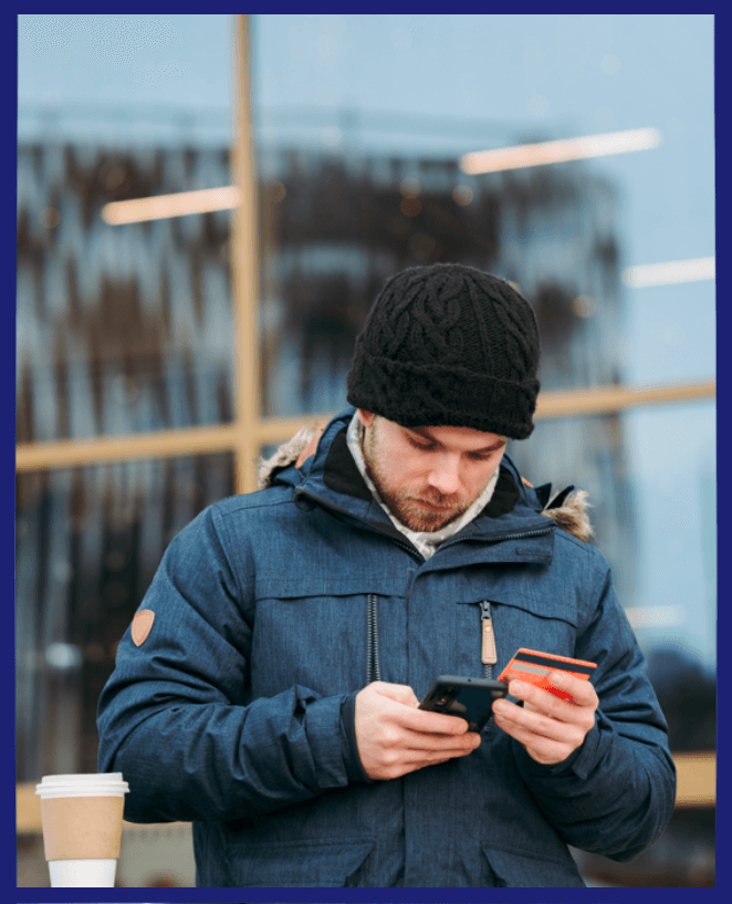 a man checking his phone with a card in other hand